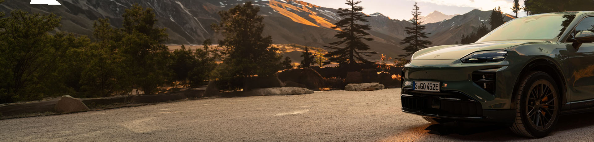 A Porsche car driving with mountains in the background